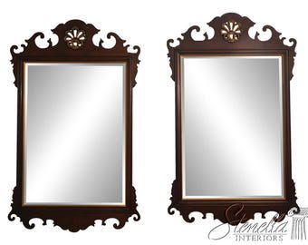 May include: Two dark brown framed mirrors with ornate, scrolled tops and bottoms. Each mirror has a rectangular reflective surface with a gold-colored inner frame. The tops feature a decorative gold-colored accent.