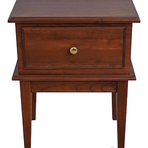 May include: A dark brown wooden end table with a single drawer and four legs. The drawer has a brass knob.