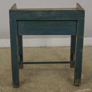 Op de afbeelding: Een donkerblauwe houten tafel met een enkele lade en een metalen steunbalk. De tafel heeft een verweerde afwerking en is geverfd in een diepe teal kleur.