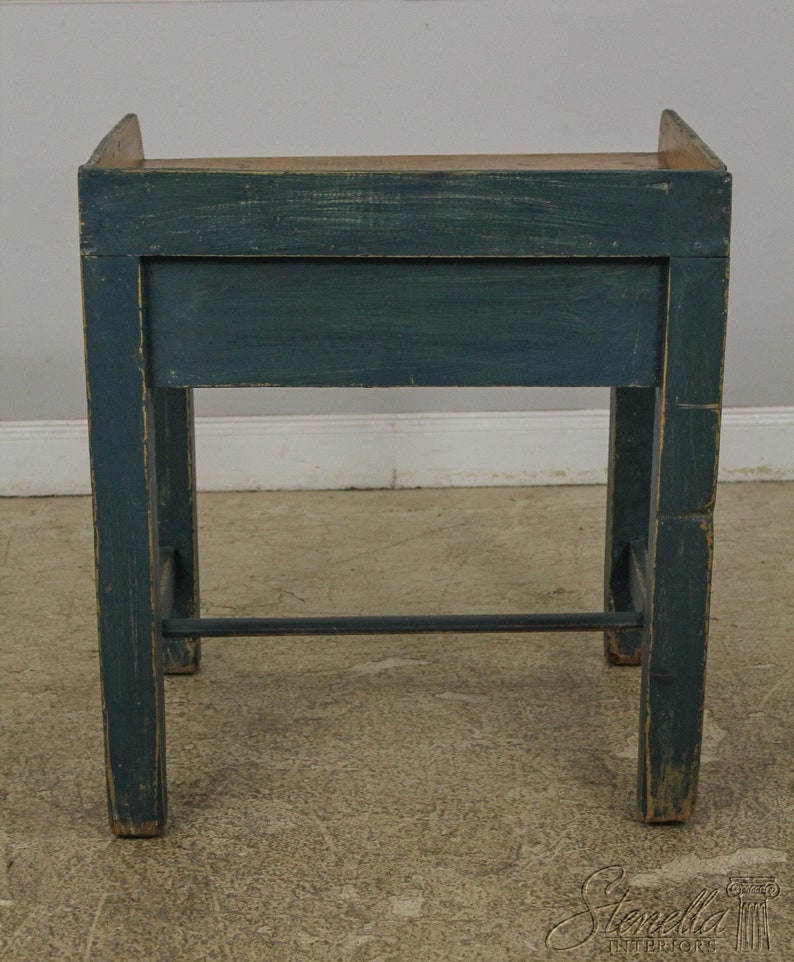 Op de afbeelding: Een donkerblauwe houten tafel met een enkele lade en een metalen steunbalk. De tafel heeft een verweerde afwerking en is geverfd in een diepe teal kleur.
