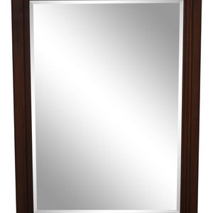 May include: A rectangular mirror with a dark brown wooden frame. The mirror's reflective surface is surrounded by a beveled edge. The frame has a simple, classic design. The bottom right corner features the text "Stenella Interiors".