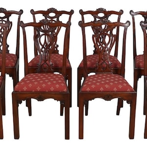 May include: Set of ten antique mahogany chairs with intricate carved backs and red upholstery. The chairs have a classic design and are in excellent condition.