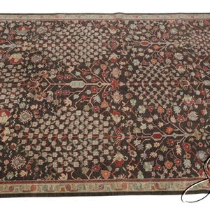 May include: A rectangular area rug featuring a dark brown background with an intricate, repeating floral and vine pattern in shades of red, cream, light blue, and green. The rug is framed by a decorative border with similar colors and motifs.