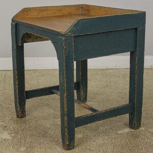 Op de afbeelding: Een donkerblauwe houten bijzettafel met een licht houten blad. De tafel heeft een eenvoudig ontwerp met &eacute;&eacute;n plank en een licht gebogen bovenrand.