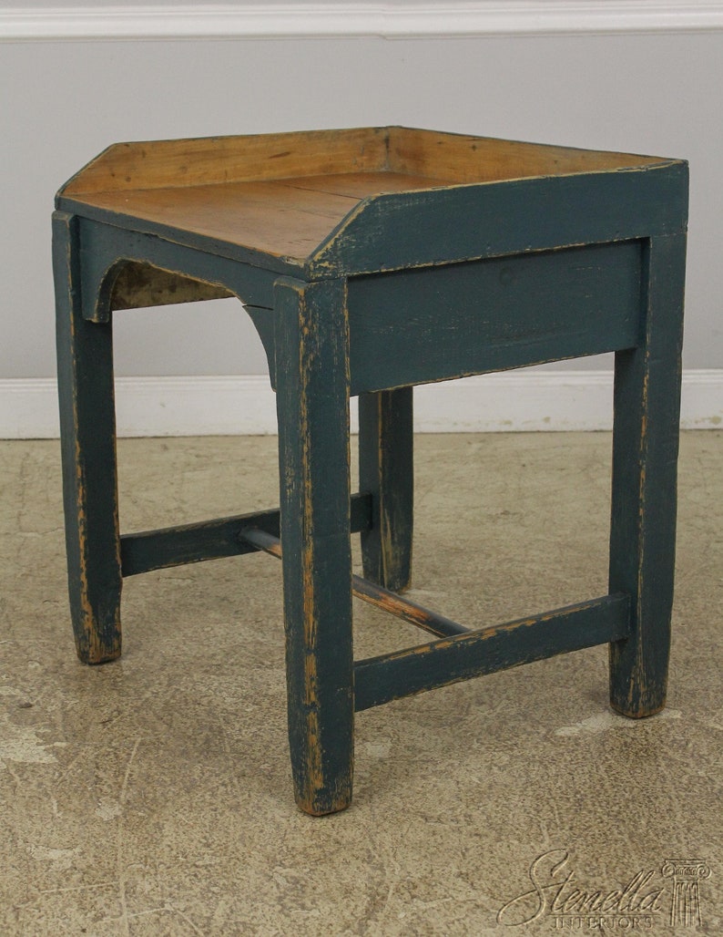 Op de afbeelding: Een donkerblauwe houten bijzettafel met een licht houten blad. De tafel heeft een eenvoudig ontwerp met &eacute;&eacute;n plank en een licht gebogen bovenrand.