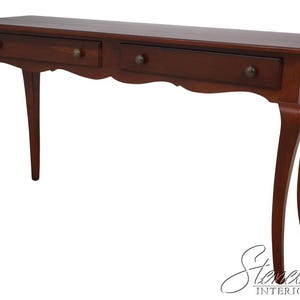 May include: A dark brown wooden console table with two drawers and brass knobs. The table has a scalloped apron and curved legs, showcasing a classic, elegant design. The table is suitable for entryways or living rooms.