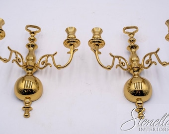 May include: Two ornate, gold-colored wall sconces. Each sconce features a central sphere, decorative arms, and candle holders. The sconces are designed to hold two candles each, adding a touch of elegance to any room.