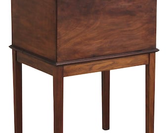 May include: A rectangular wooden chest with a dark brown finish, featuring a hinged lid and a small circular keyhole on the front panel. The chest is supported by four straight, slender wooden legs that form a base stand for the elevated storage unit.