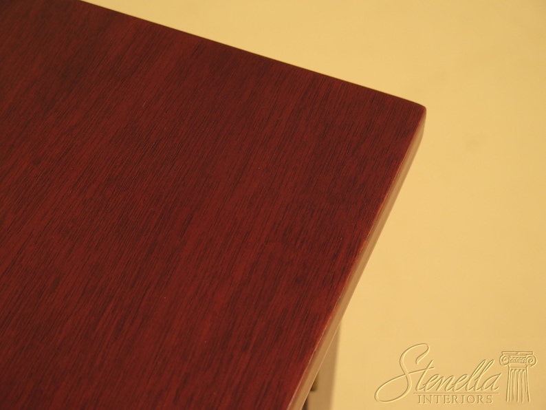Pu&ograve; includere: Primo piano di un piano da tavolo in legno rosso scuro. La venatura del legno &egrave; visibile e la superficie &egrave; liscia.
