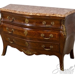 May include: A three-drawer antique chest of drawers with a marble top. The chest features a curved front, ornate brass hardware, and decorative accents. The wood has a dark brown finish with a chevron pattern on the drawer fronts.