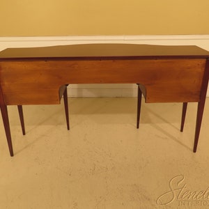 Pu&ograve; includere: Un credenza in legno di mogano con un piano curvo e quattro gambe. La credenza ha un interno in legno chiaro ed &egrave; mostrata dal retro.