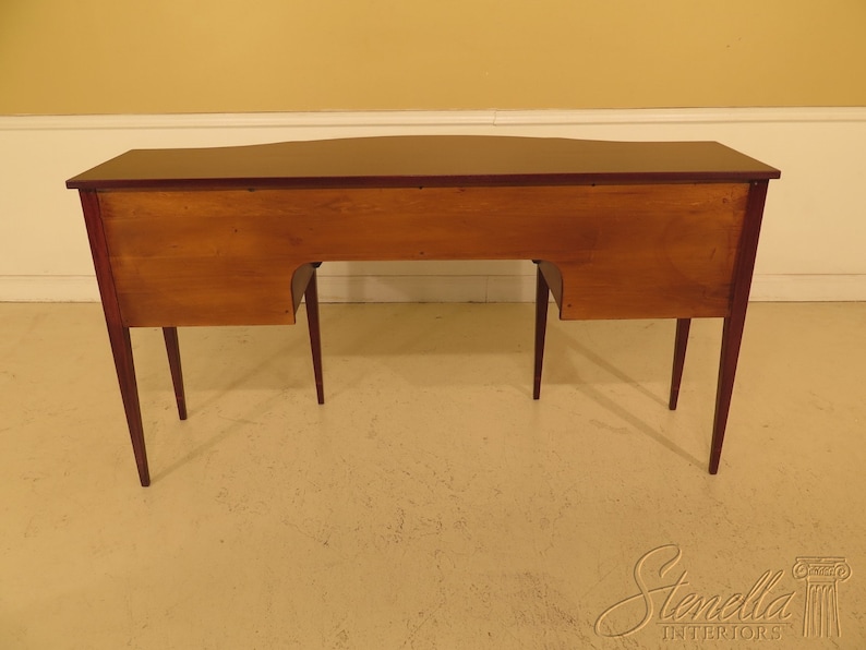 Pu&ograve; includere: Un credenza in legno di mogano con un piano curvo e quattro gambe. La credenza ha un interno in legno chiaro ed &egrave; mostrata dal retro.