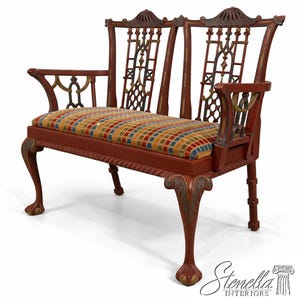 May include: A red bench with a patterned seat cushion and ornate detailing. The bench features curved armrests, decorative back supports, and carved legs. The seat cushion has a colorful plaid pattern.