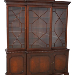 May include: A mahogany wood three-door cabinet with glass doors and a decorative top. The cabinet has two lower doors with a raised panel design. The cabinet is a traditional style with a rich wood finish.