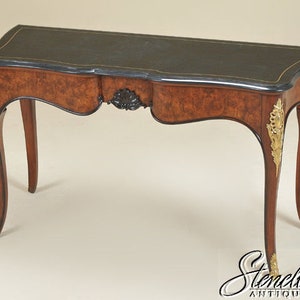 May include: A French-style console table with a black leather top and intricate wood marquetry. The table has ornate gold accents and curved legs.