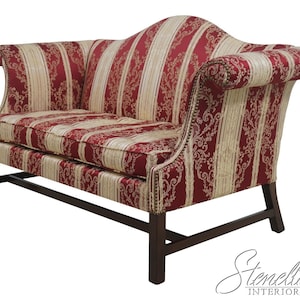 May include: A two-seater sofa with a dark wood frame. The upholstery features a red and cream striped pattern with a floral design. The sofa has curved arms and a straight back, showcasing a classic design.
