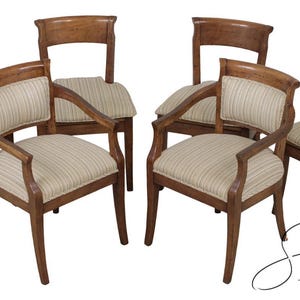 May include: A set of six wooden dining chairs. The chairs have a light brown finish with striped fabric seats and backs. Two chairs have armrests. The chairs are arranged on a white background.