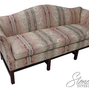 May include: A curved, striped sofa with a floral pattern in shades of pink, green, and beige. The sofa has wooden legs and a curved back.
