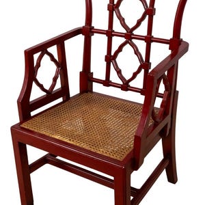 May include: A burgundy-colored armchair with a woven seat and decorative back. The chair features a lattice design on the back and armrests. The chair is made of wood and has a classic, elegant style.