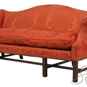 May include: A sofa upholstered in orange fabric with a tonal damask pattern, featuring a curved backrest, rolled arms, and a single seat cushion. The base is supported by dark brown wooden legs connected by a horizontal stretcher frame.