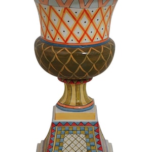 May include: A large, hand-painted ceramic planter with a geometric design. The planter is in shades of yellow, orange, red, blue, and green. It has a wide, round top and a tall, slender base.