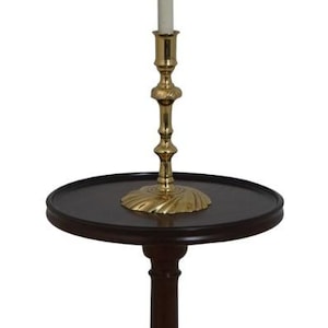 May include: A mahogany floor lamp with a white pleated lampshade and a brass base. The lamp has a round table top with a dark wood finish.