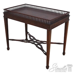 May include: A mahogany wood serving table with a decorative carved edge and a cross-shaped base. The table has a raised edge around the top.