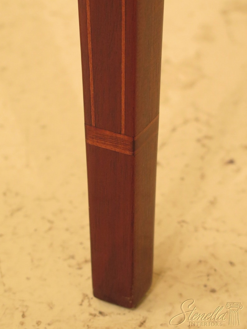 Pu&ograve; includere: Primo piano di una gamba di tavolo in mogano con strisce di legno intarsiate. La gamba &egrave; quadrata e ha una finitura marrone rossiccio scuro.