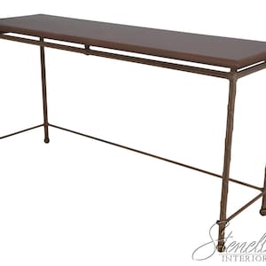 May include: A long, rectangular console table with a dark brown top and a bronze-colored metal frame. The frame has a textured, branch-like design on the legs and a simple, linear design for the supports. The table is approximately 60 inches long.