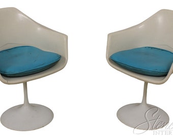 May include: Two white swivel chairs with blue cushions. The chairs have a unique, modern design.