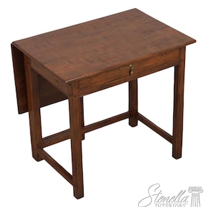 May include: A small, antique wooden table with a rectangular top and a single drawer. The table is a warm brown color and has a drop-leaf on one side. The table is approximately 30 inches long, 20 inches wide, and 28 inches high.