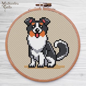 A charming cross-stitch embroidery artwork featuring a playful dog, depicted in a pixelated style. The dog, primarily black with white and tan markings, sits with its tongue out, exuding a cheerful demeanor. This design, framed in a wooden embroidery hoop, rests on a light wooden surface, highlighting its craftmanship. Ideal for pet lovers, this unique piece is perfect for home decor or as a thoughtful gift. Perfect for anyone looking to add a touch of whimsy to their space!