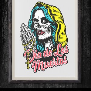 Puede incluir: Patr&oacute;n de punto de cruz con una mujer esqueleto con cabello azul y capucha amarilla, rezando con un rosario. El texto "Dia de Los Muertos" est&aacute; escrito en rosa y negro debajo de la mujer. El patr&oacute;n mide 11,13 pulgadas por 16,06 pulgadas y utiliza 5 colores.