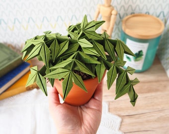 May include: A green origami plant in a terracotta pot. The plant is made of folded paper and has a realistic appearance.