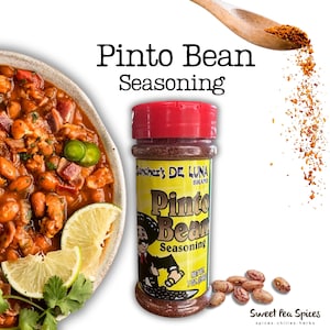 May include: A jar of Pinto Bean Seasoning by Sanchez's De Luna Brand, with a red lid and yellow label. The label features a cartoon character and the text "Pinto Bean Seasoning". A bowl of pinto beans with lime wedges is on the left.