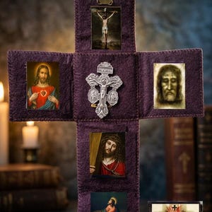 Pode incluir: Um objeto religioso em forma de cruz, roxo, com várias imagens emolduradas. As imagens retratam figuras e cenas religiosas, incluindo Jesus Cristo e o Sagrado Coração. Um crucifixo prateado está preso ao centro. O item é exibido em uma superfície escura.