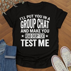 Könnte beinhalten: Schwarzes T-Shirt mit weißem Text: "I'LL PUT YOU IN A GROUP CHAT AND MAKE YOU READ EVERY TEXT TEST ME". Das Shirt wird mit blauen Jeans und weißen Turnschuhen gezeigt.