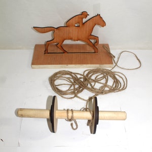 May include: Wooden toy horse and rider with a brown wooden base and a spool with twine attached. The horse and rider are brown and the spool is brown with black ends.