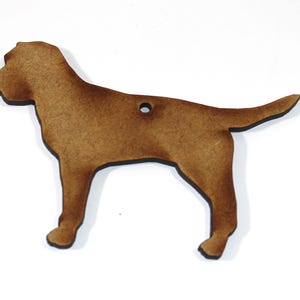 May include: A brown wooden dog ornament with a hole for hanging. The dog is standing with its legs straight and its tail curled up.