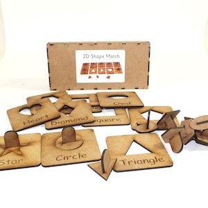 May include: Wooden 2D shape matching game with a box and pieces labelled with the names of the shapes: heart, diamond, square, oval, star, circle, triangle.