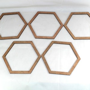 May include: Five unfinished wooden hexagonal frames, arranged in a staggered pattern on a white surface.
