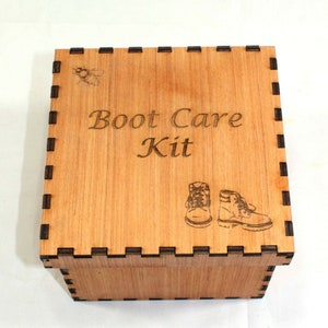 May include: A wooden box with a black trim and the words "Boot Care Kit" engraved on the top. The box has a small image of a bee and two boots on the front.