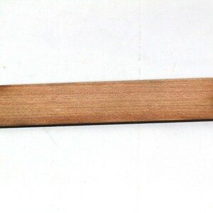 May include: A plain, rectangular wooden bookmark with a small hole in the top right corner.