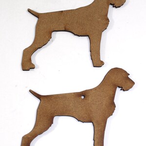 May include: Two brown wooden dog cutouts. The cutouts are in the shape of a dog, with a tail, four legs, and a head. One cutout has a hole near the top. The cutouts are on a white background.