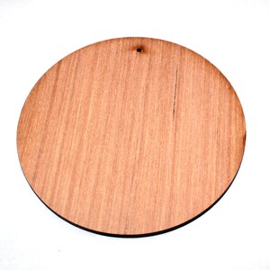 May include: A round, unfinished wooden disc with a hole in the centre. The disc is light brown in colour and has a wood grain pattern.
