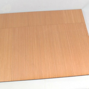 May include: Two sheets of light brown wood veneer, stacked on top of each other.