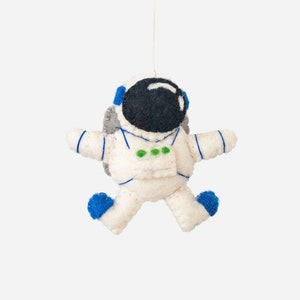 May include: A white felt astronaut ornament with blue accents and a black felt helmet. The ornament is hanging from a white string.