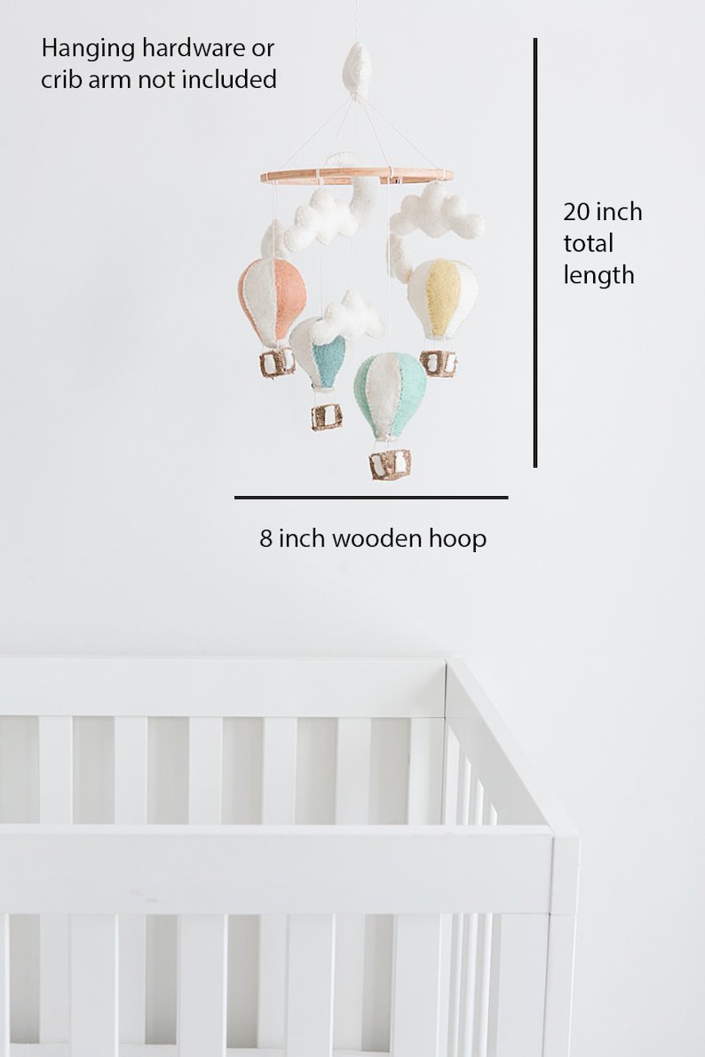 Op de afbeelding: Een baby mobile met kleurrijke vilten luchtballonnen en witte wolkenaccenten. De mobile hangt aan een houten ring, met een totale lengte van 50.8 cm. De houten ring heeft een diameter van 20.3 cm.