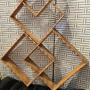 May include: A wooden wall shelf with a diamond pattern. The shelf has multiple compartments and is made of natural wood.