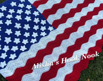 May include: A crocheted blanket featuring a red, white, and blue chevron pattern with white stars appliqued on a blue field. The text Alisha's Hook Nook is printed in white across the lower section of the blanket, which mimics the American flag.